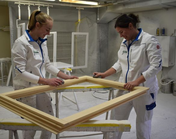 Zwei Mitarbeiterinnen der Malergeschäft R. & M. Schuler GmbH arbeiten an einem Rahmen