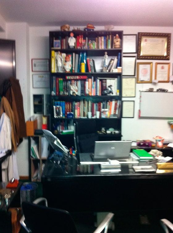 Una oficina muy desordenada con una computadora portátil en el escritorio.