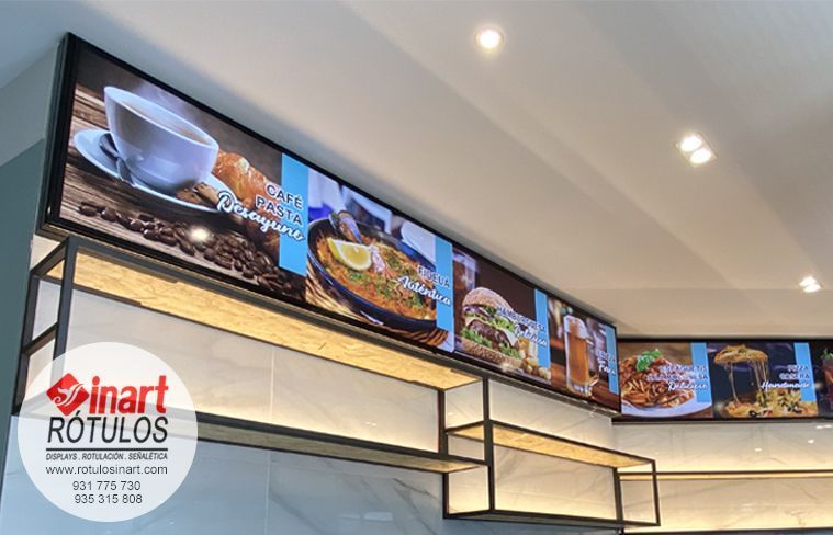 Un expositor de restaurante con menús retroiluminados que muestran la comida y las bebidas, montado sobre una estantería metálica negra.