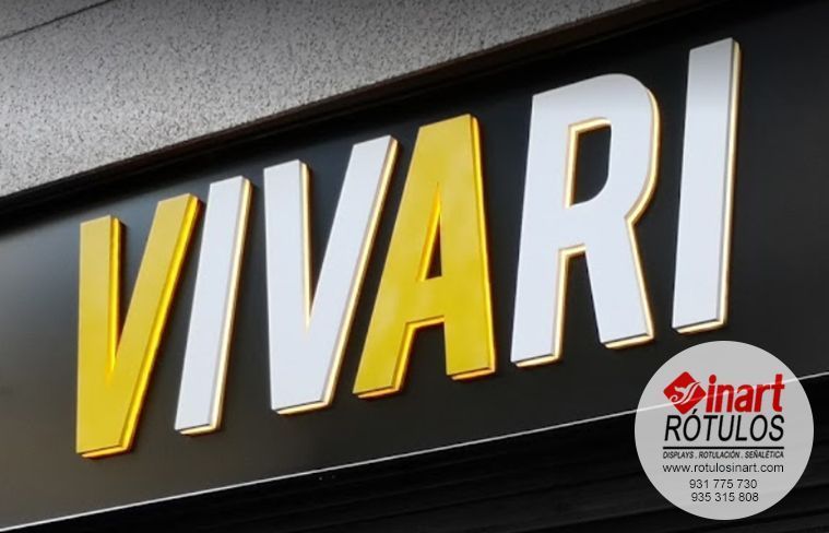 Un letrero de VIVARI con letras 3D amarillas y blancas alternadas sobre un fondo negro, con una pequeña pegatina del logotipo de Inart Rótulos.