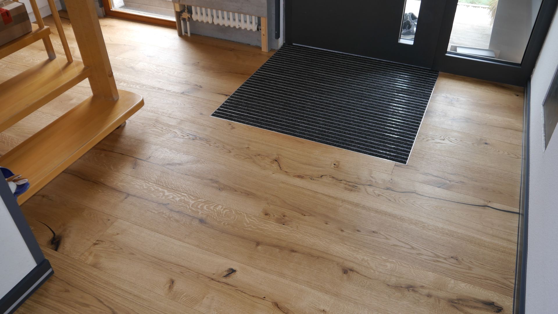 Ein Holzboden mit einer schwarzen Matte vor einer Tür.