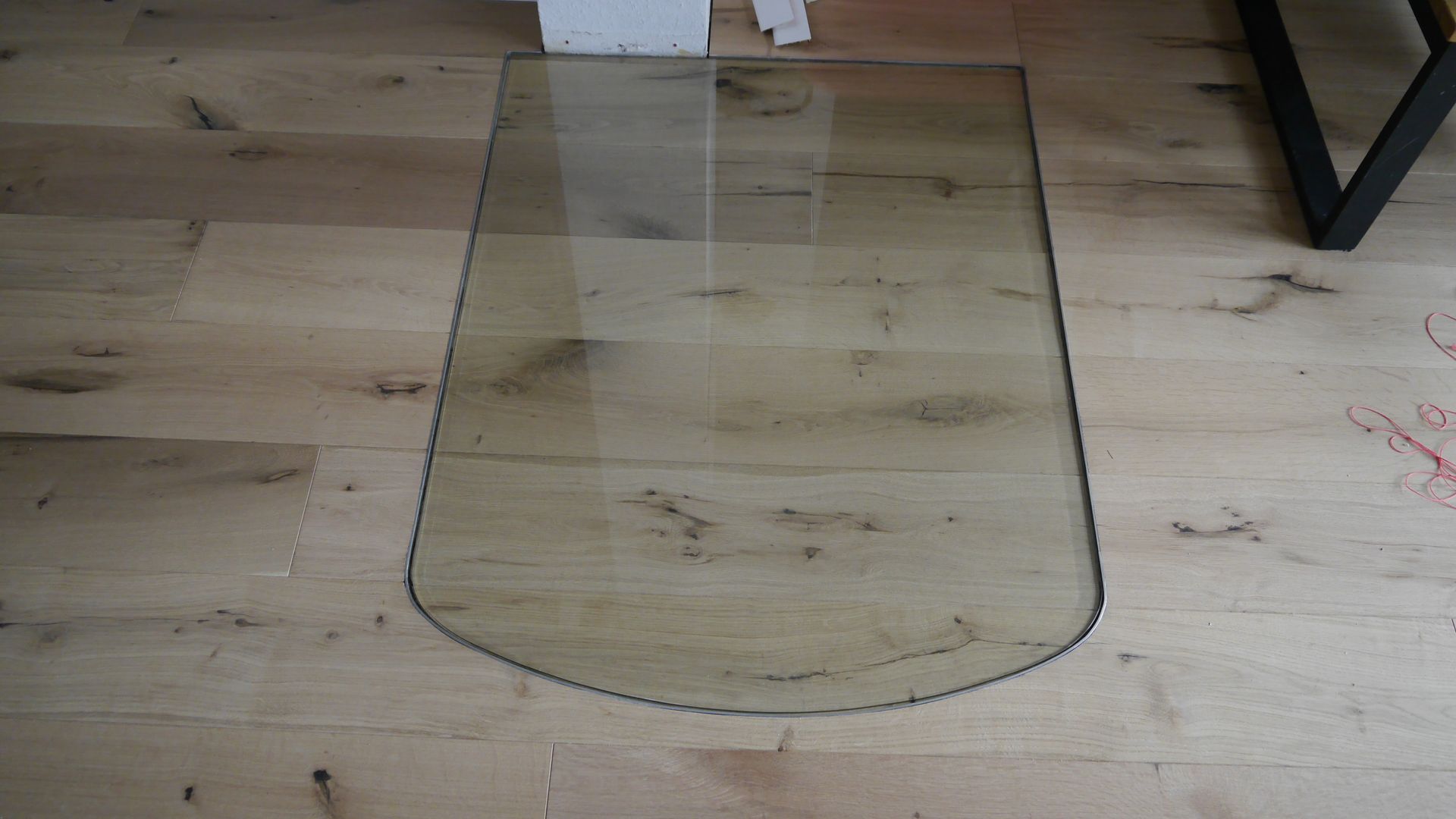 Auf einem Holzboden liegt ein Stück Glas.