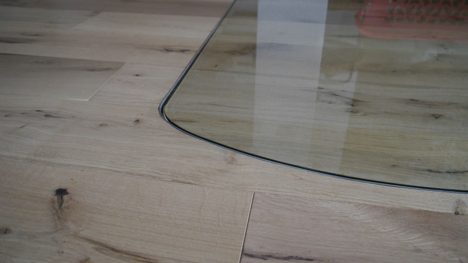 Eine Nahaufnahme eines Holzbodens mit einer Glastischplatte.