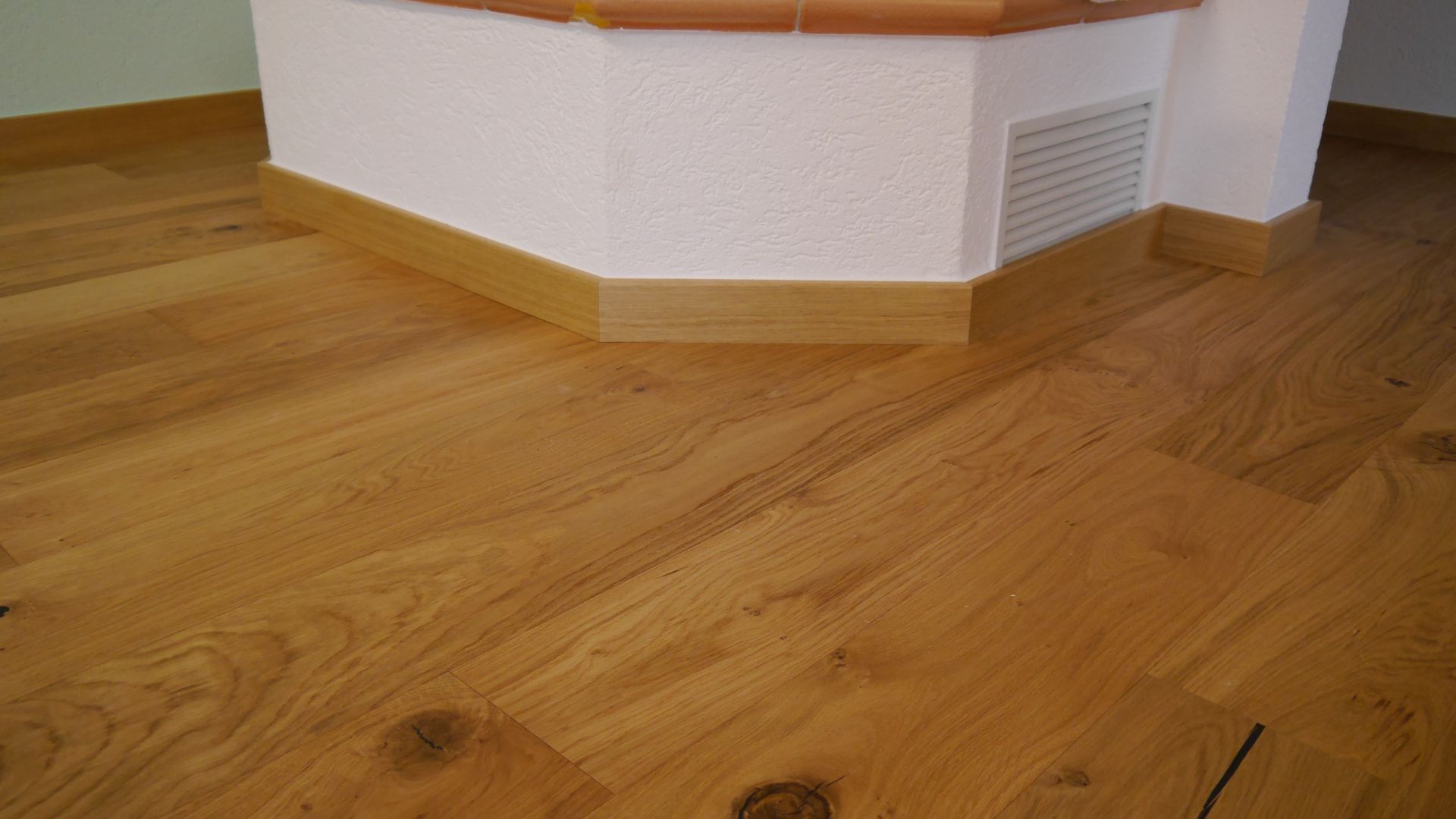 Ein Holzboden neben einem Kamin in einem Zimmer.