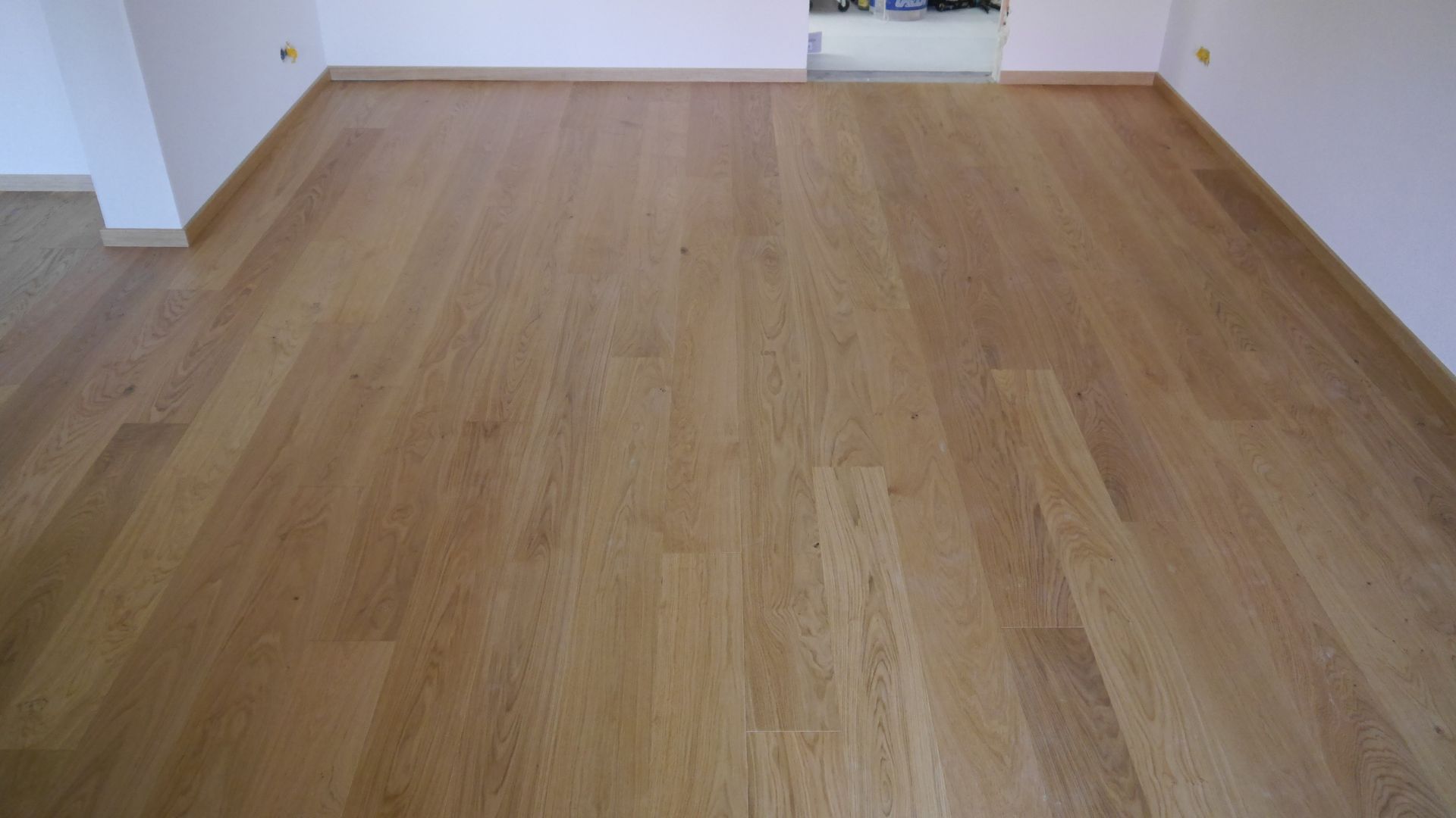 Ein Wohnzimmer mit Holzboden und weißen Wänden.