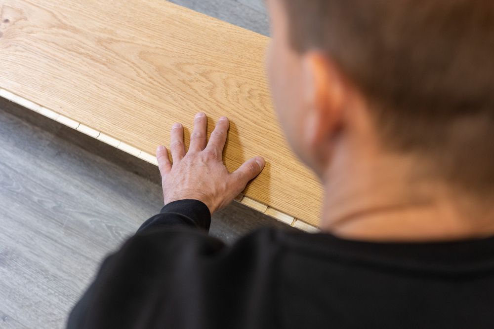 Timo Teich verlegt ein Holzparkett.