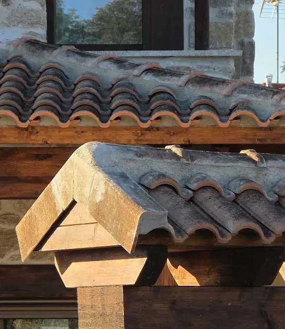 Detalle de cubierta de teja de barro, con tejas de terracota desgastada y estructura de madera.