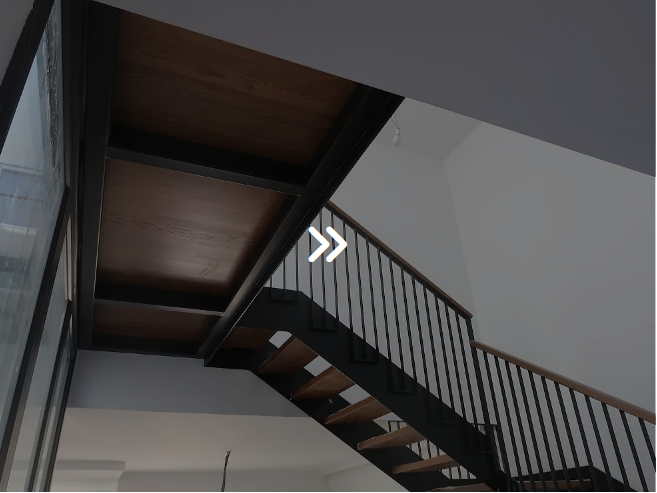 Escalera con peldaños de madera, barandilla negra y vigas. Vista interior.