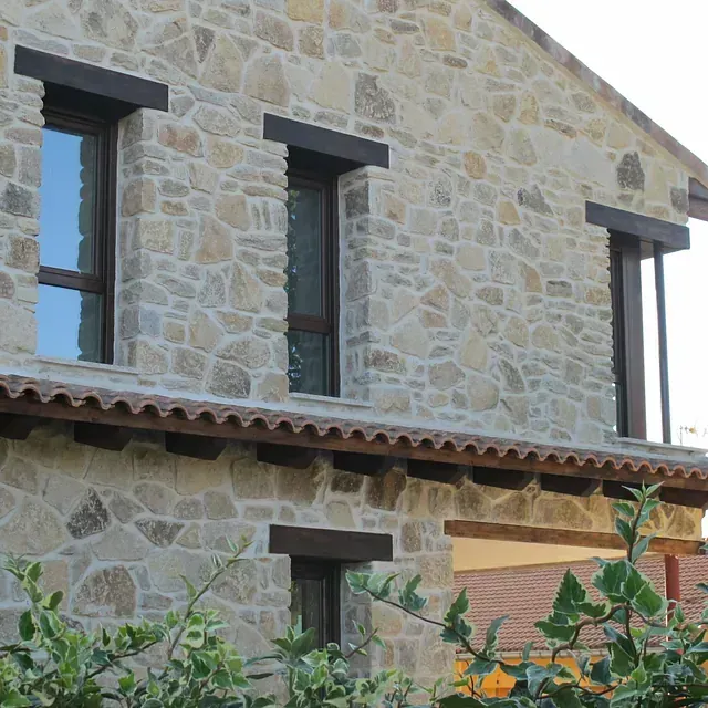 Casa de piedra con marcos de ventanas de color marrón oscuro.