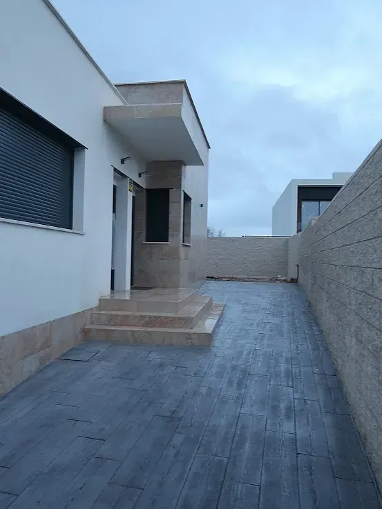 Exterior de casa moderna con pasarela de hormigón y escalones que conducen a la entrada.