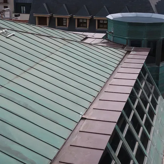 Cubierta de cobre verde con múltiples tramos y torre cilíndrica.