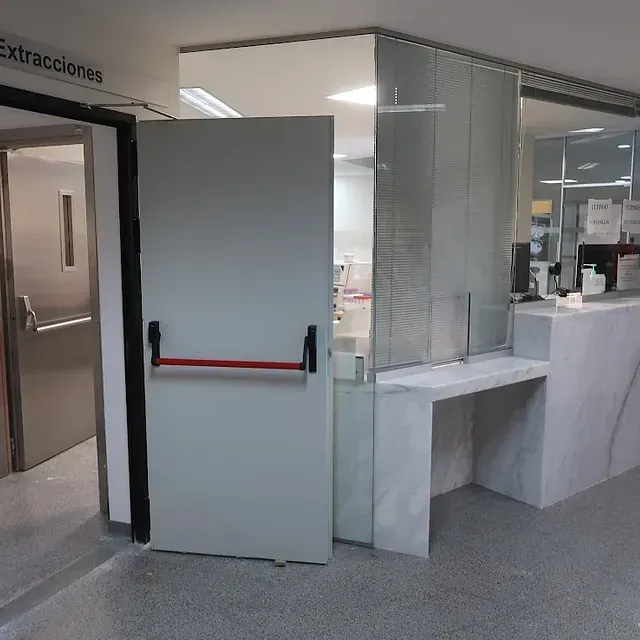 Puerta abierta con manija roja que conduce a la recepción del consultorio médico.