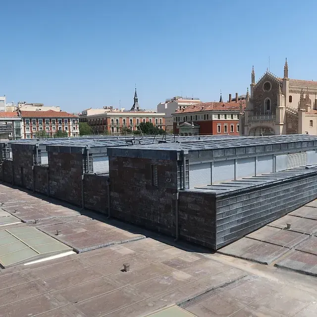 Vista de la azotea en Madrid con edificios de diferentes estilos y una iglesia bajo un cielo despejado.