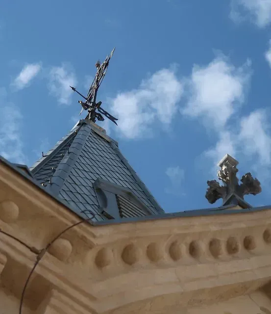 Techo ornamentado detallado con elementos decorativos, contra un cielo azul con nubes.