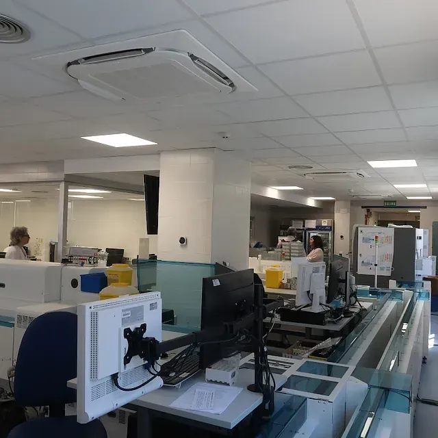 Un entorno de laboratorio de oficina con computadoras, equipos de laboratorio y gente trabajando.