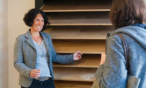 Zwei Frauen stehen nebeneinander vor einem Holzregal.