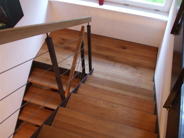 Eine Holztreppe mit einem Metallgeländer und einem Fenster