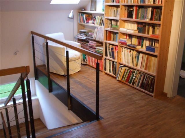 Eine Treppe führt zu einer Bibliothek mit vielen Büchern in den Regalen