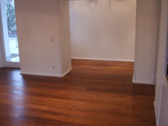 Ein leerer Raum mit Holzboden und weißen Wänden