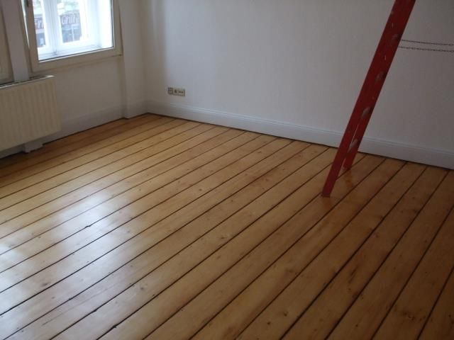 Ein Raum mit Holzboden und einer roten Leiter