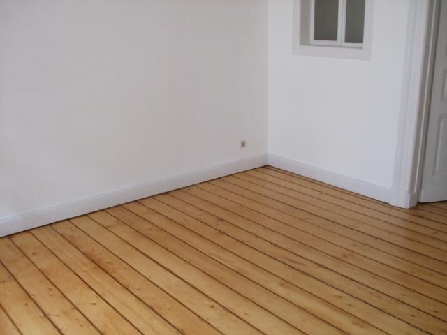 Ein leerer Raum mit Holzboden und weißen Wänden