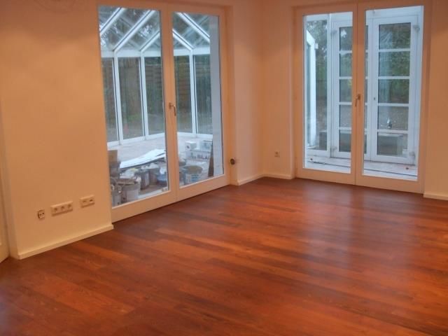 Ein leerer Raum mit Hartholzböden und Glasschiebetüren