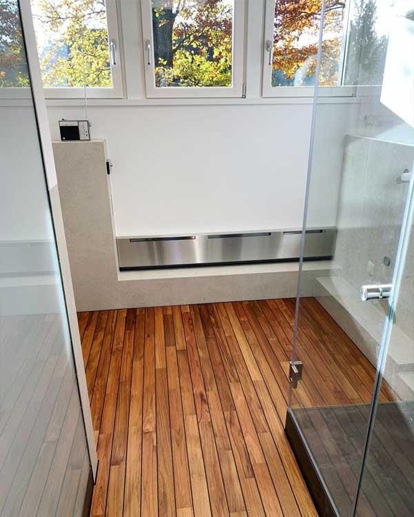 Ein Badezimmer mit Holzboden und einer Glasduschtür