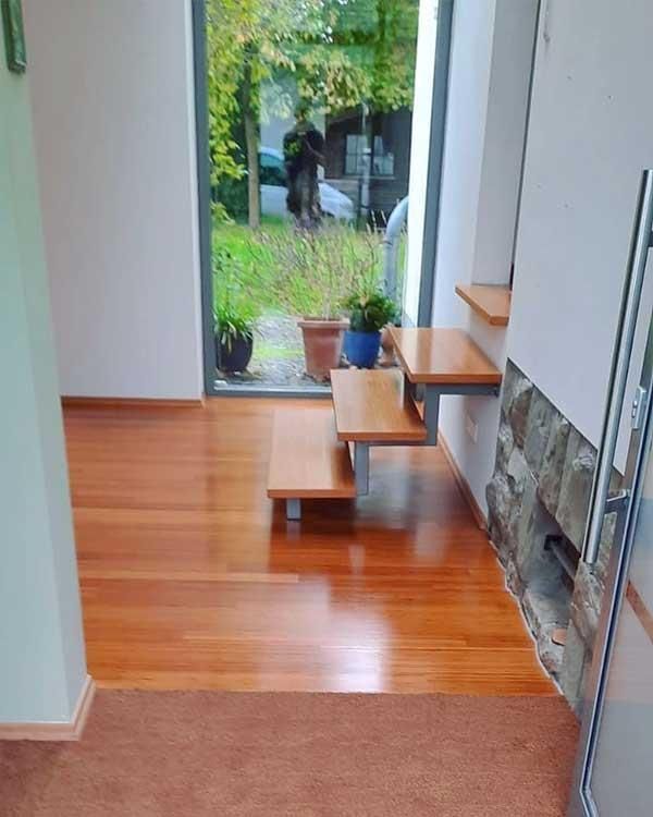 Ein Raum mit Holzboden und einer Treppe, die zu einem Fenster führt.