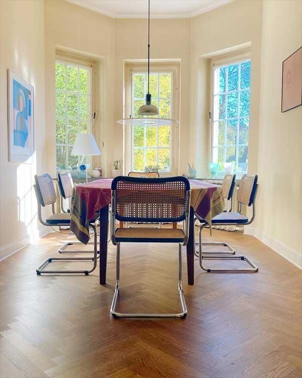 Ein Esszimmer mit einem Tisch und Stühlen vor einem Fenster.