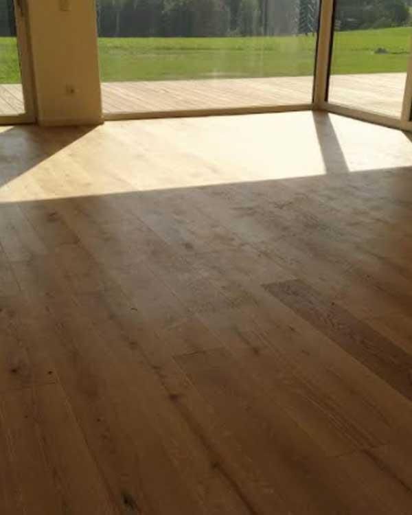 Ein Raum mit Holzboden und großem Fenster.