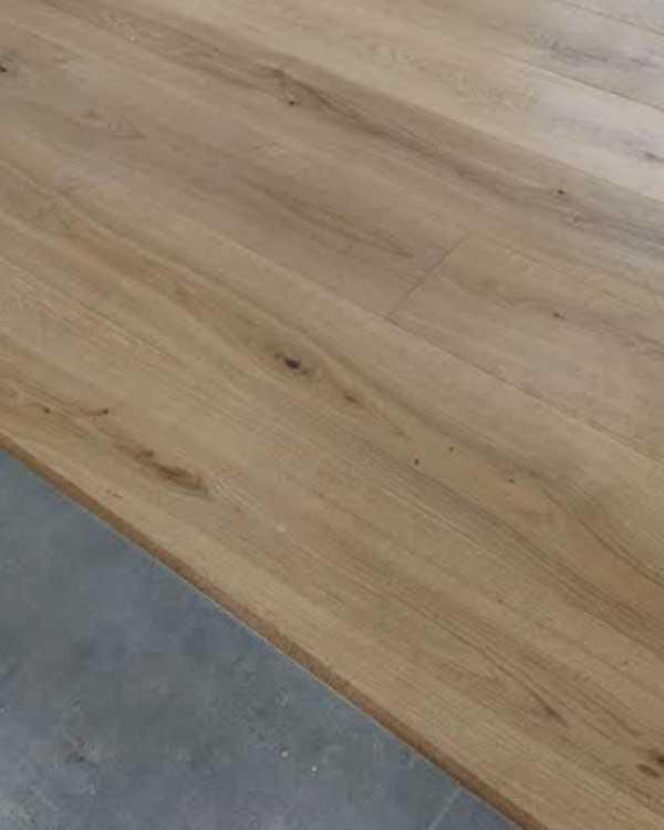 Eine Nahaufnahme einer hölzernen Tischplatte auf einem Betonboden.