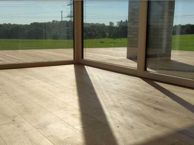 Ein Zimmer mit Holzboden und einem großen Fenster mit Blick auf ein Feld.