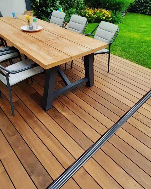 Eine Holzterrasse mit Tisch und Stühlen darauf