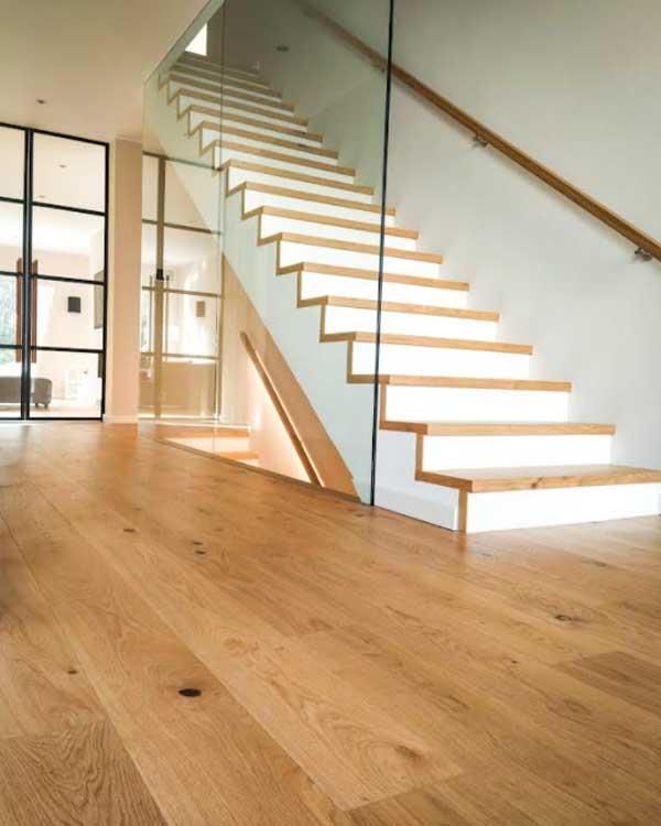 Eine Holztreppe mit weißen Stufen und einem Glasgeländer.