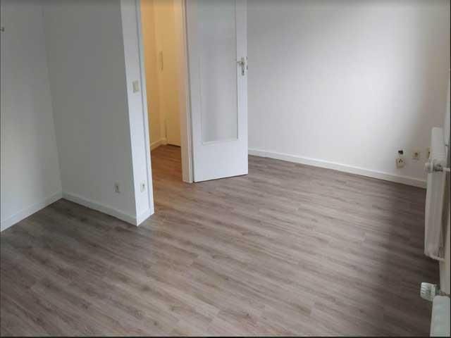 Ein leerer Raum mit Holzboden und weißen Wänden.