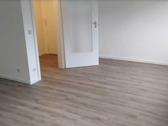 Ein leerer Raum mit Holzboden und einer Tür.