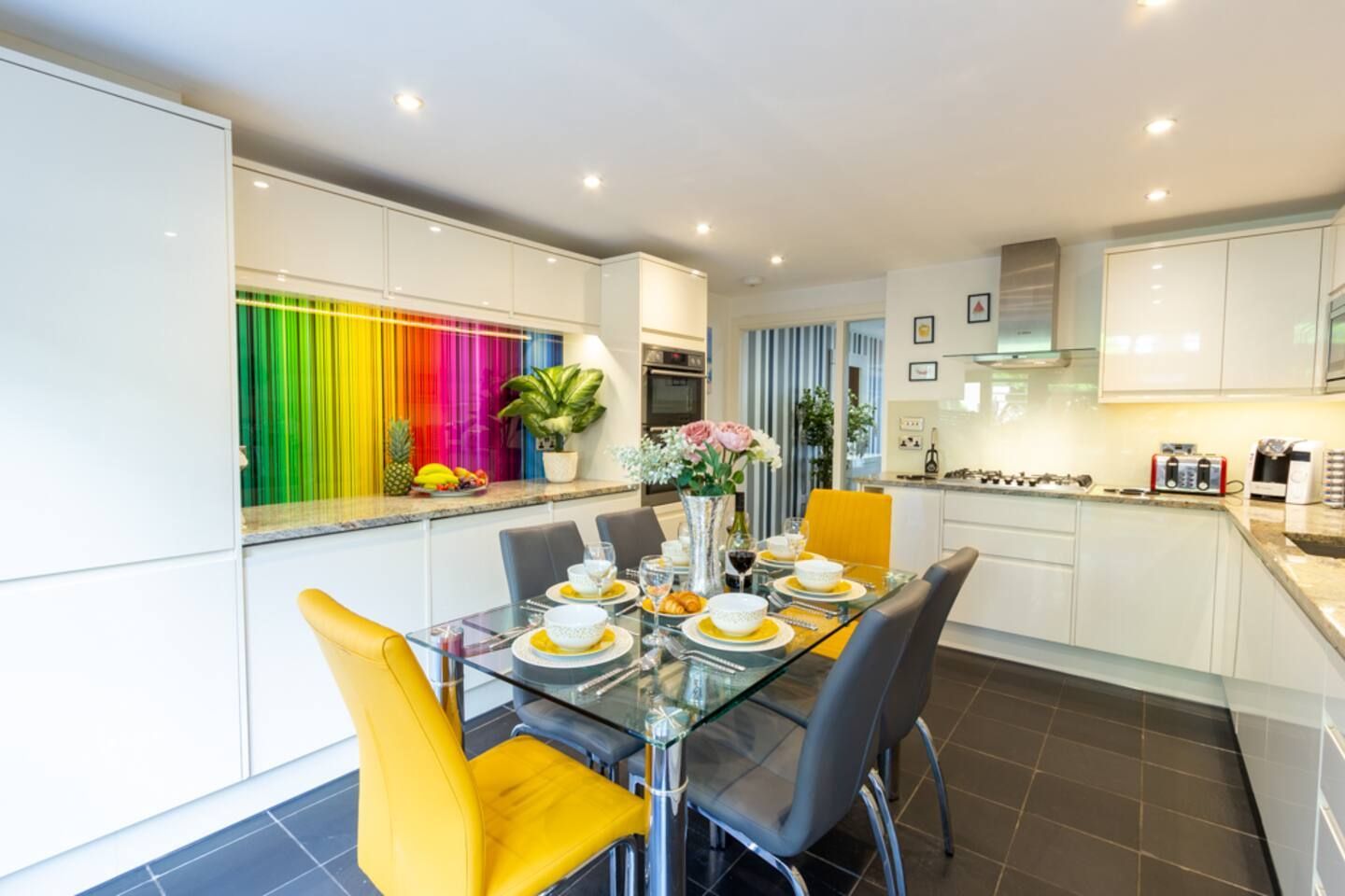 A kitchen with a glass table and yellow chairs