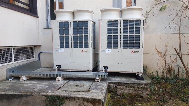 Deux grandes unités de climatisation industrielles blanches à l'extérieur d'un bâtiment.