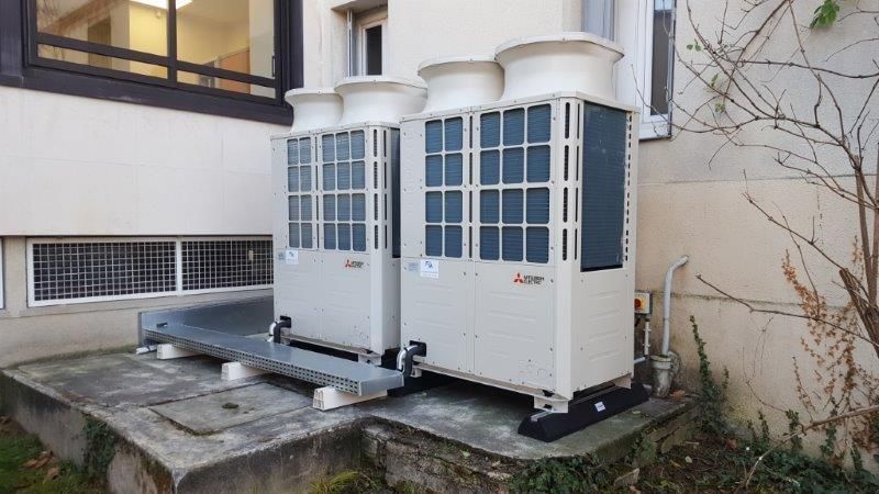 Deux grandes unités de climatisation beiges à l'extérieur d'un bâtiment.