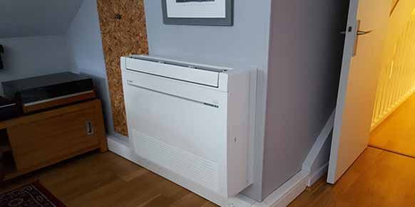 Un climatiseur blanc installé sur un mur à côté d'une porte.