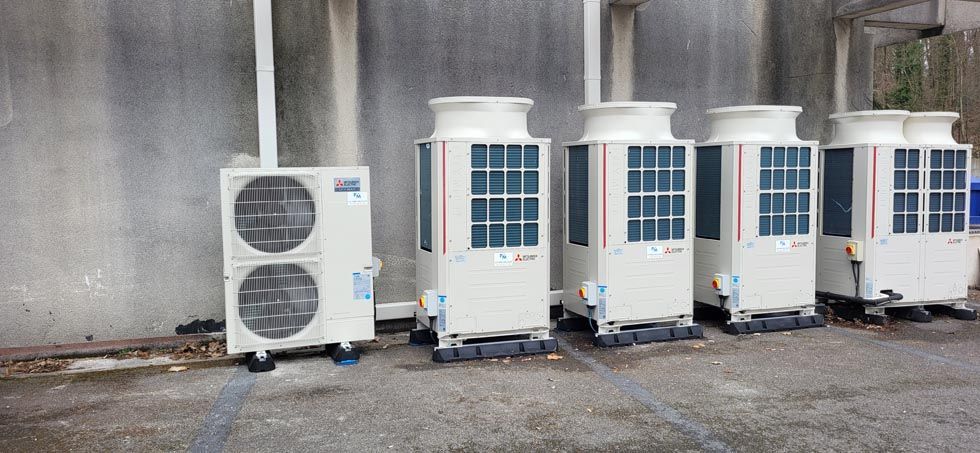 Des unités de climatisation alignées contre un mur.