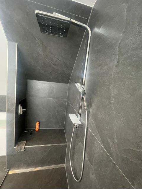 In einem Badezimmer hängt ein Duschkopf von der Decke.