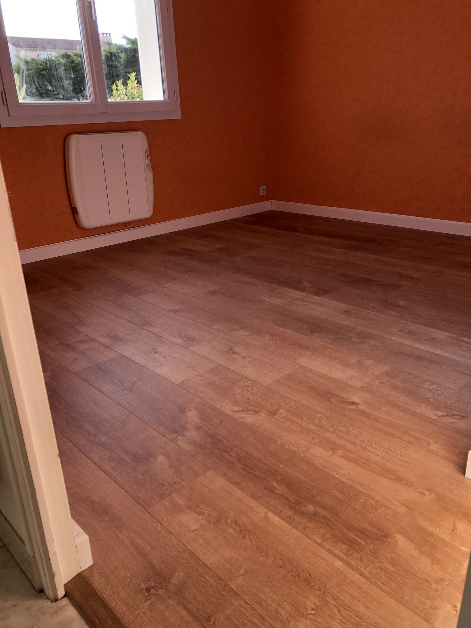 Pose de sol stratifié dans une chambre avec peinture terracotta