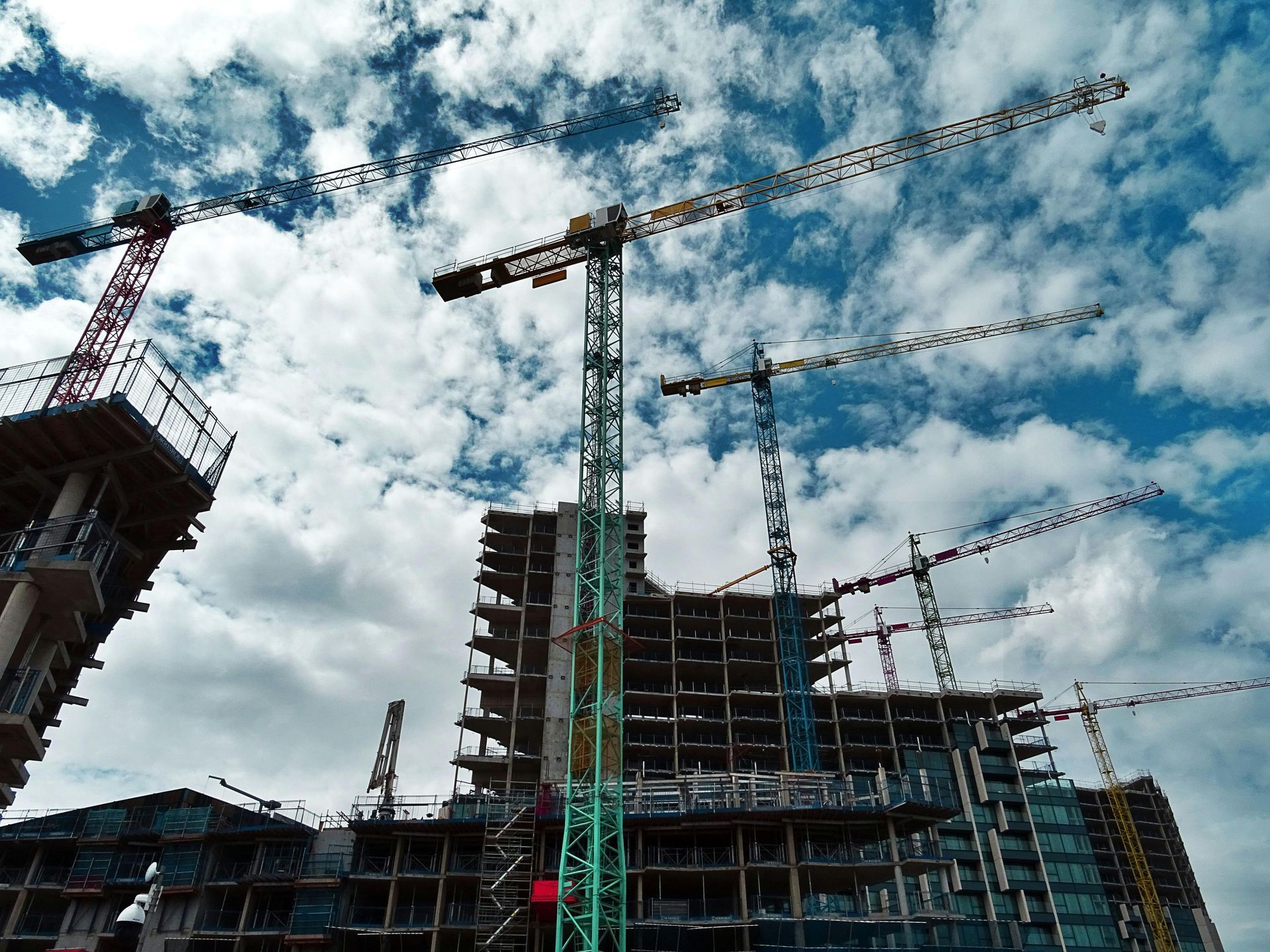 Se está construyendo un edificio con grúas y un cielo azul al fondo.