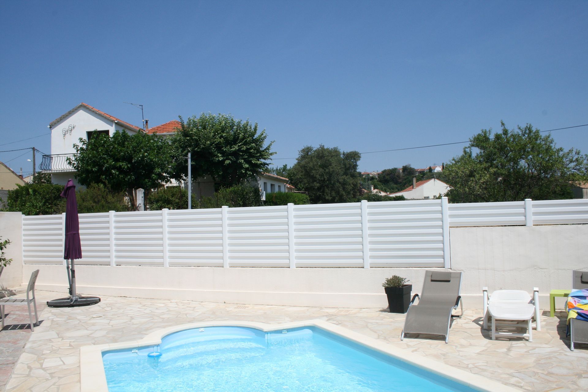 Coin d'une piscine avec une clôture blanche au loin