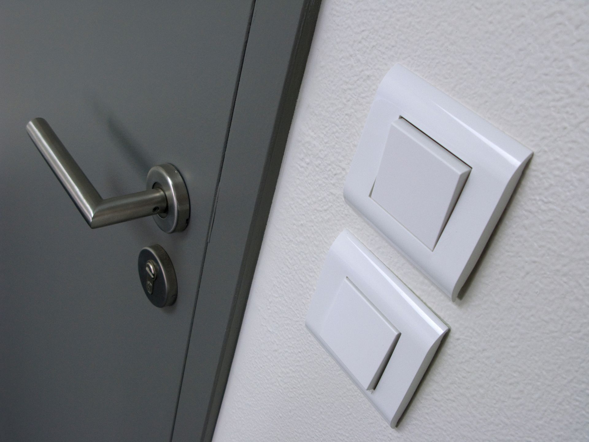 Deux interrupteurs à côté d'une porte en aluminium fermée