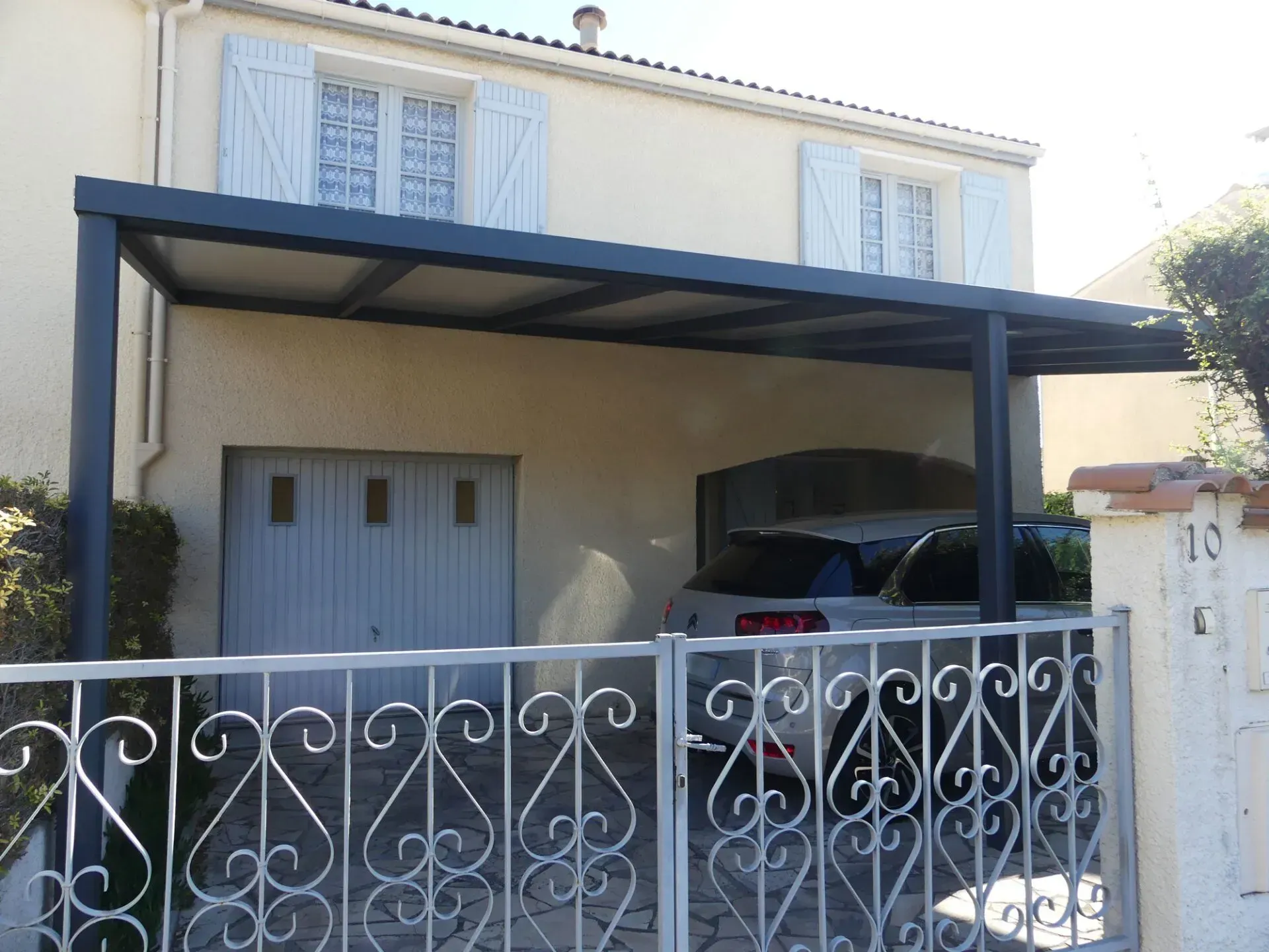 Porte de garage et véhicule gris sous un carport