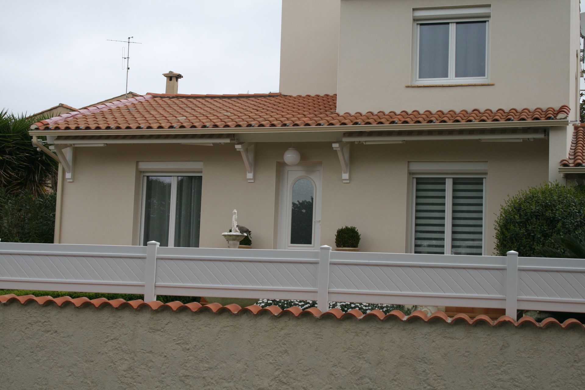 Maison sur deux niveaux derrière une clôture en PVC