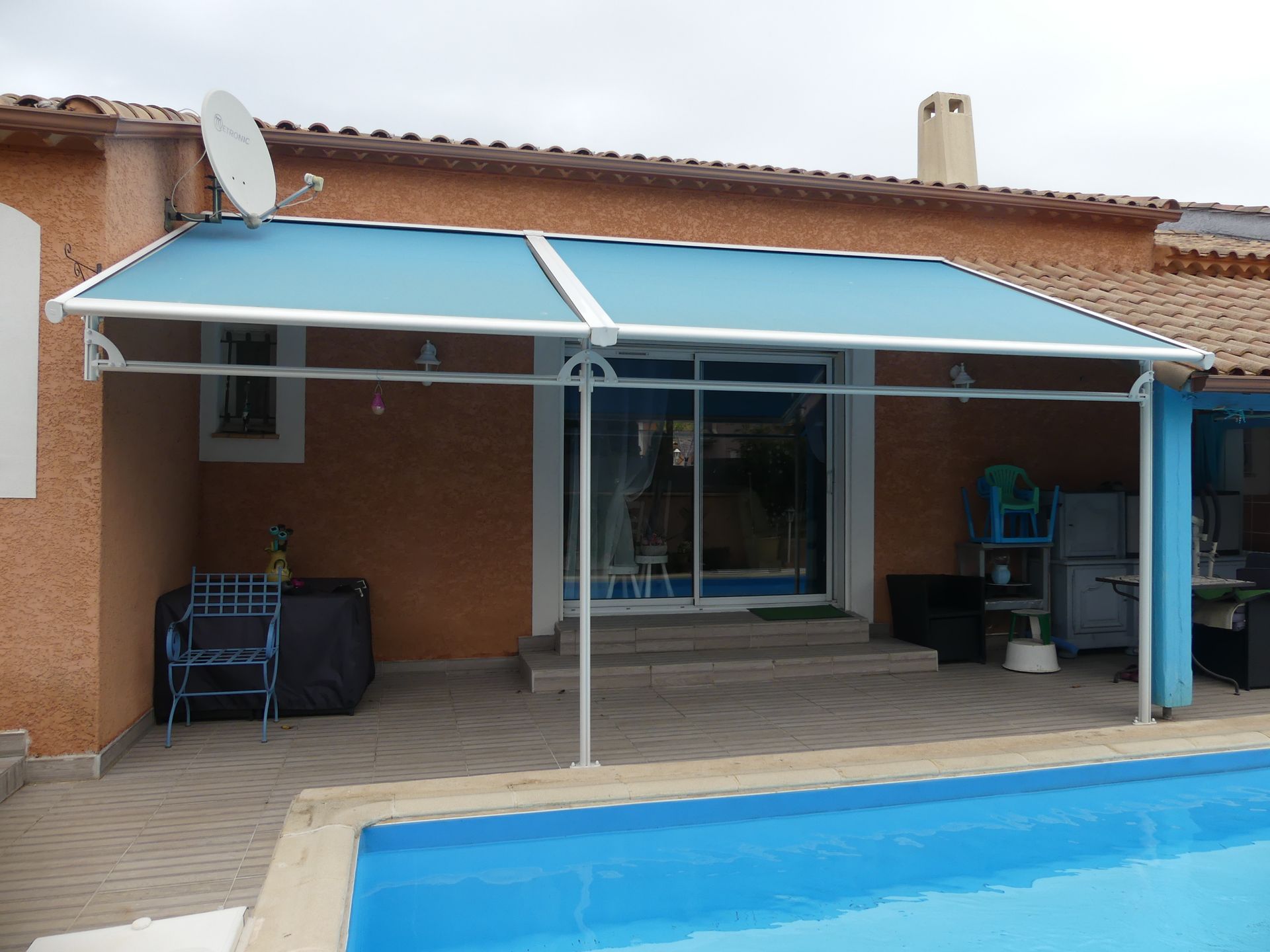 Store de couleur bleue devant une maison au bord d'une piscine