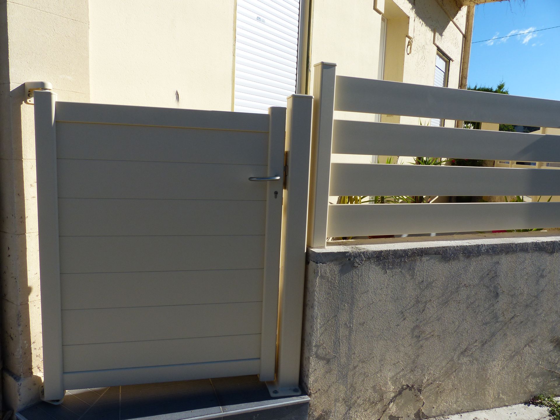 Petit portillon fermé et une clôture sur un muret